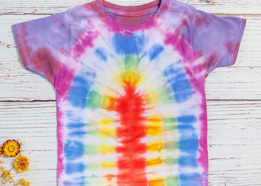 A rainbow tie dye t - shirt on a wooden table.