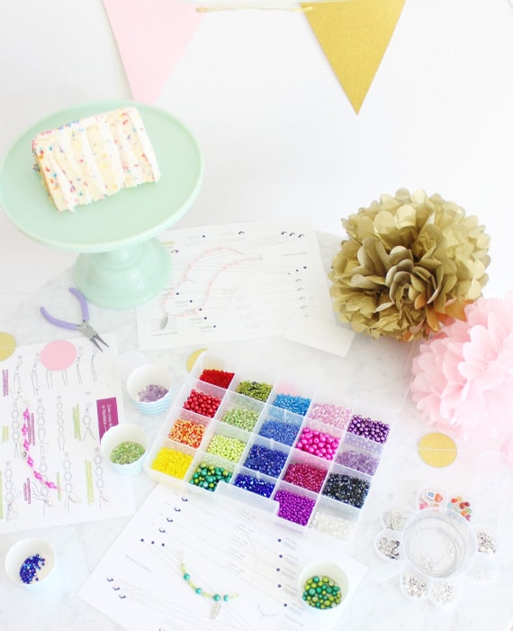 A table full of supplies for making a beaded birthday cake.