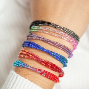A woman's wrist with colorful beaded bracelets on it.