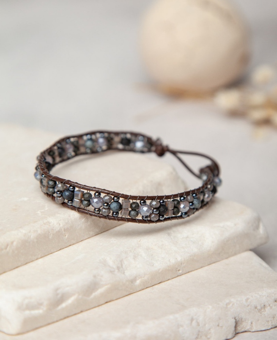 A bracelet with blue and brown beads on top of a stone.