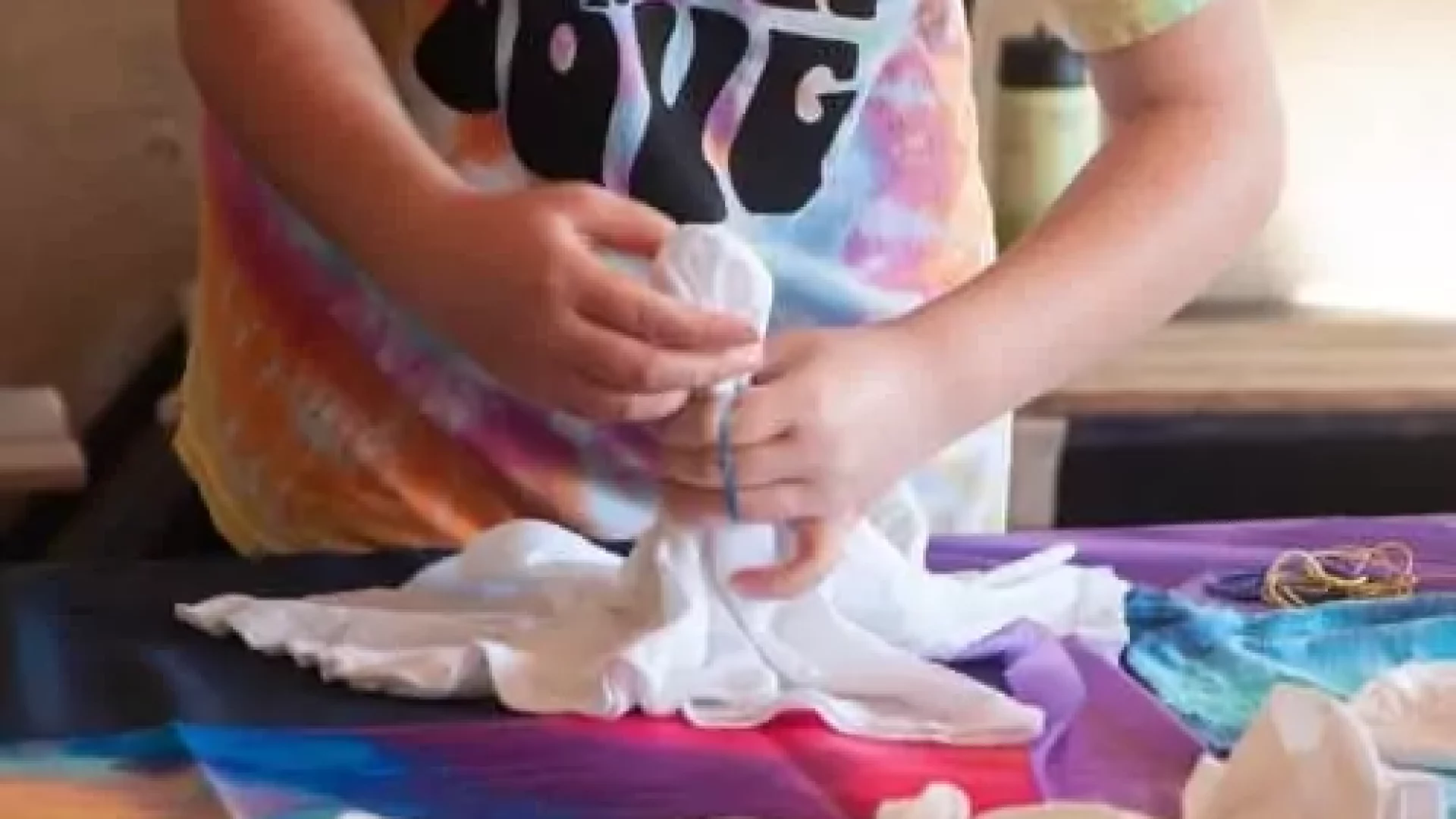 A girl is making a Kids Tie-Dye Party - San Diego Area t-shirt.